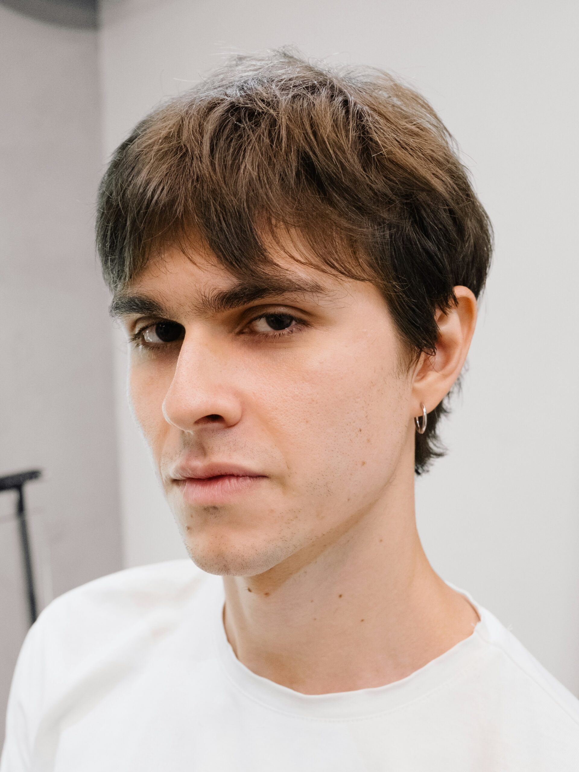 A young man with a business mullet haircut wearing a white t-shirt.