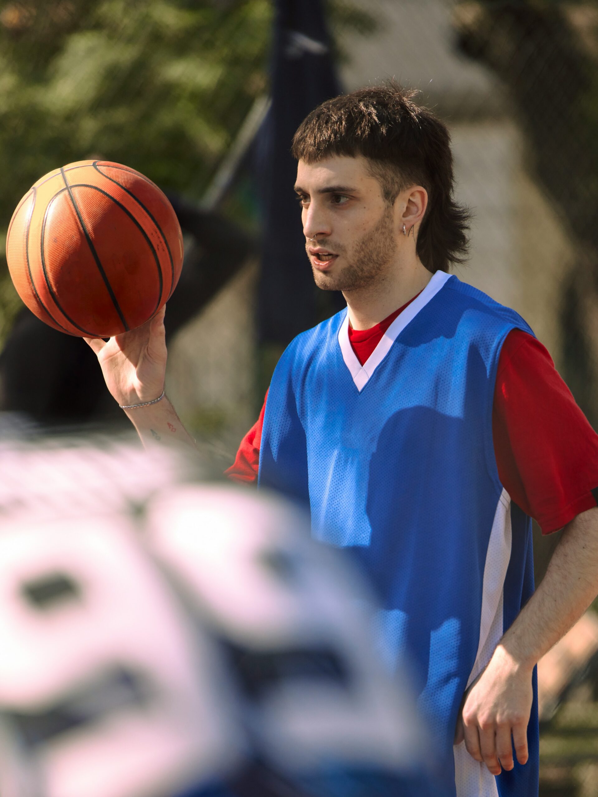 A young man with a fade mullet haircut playing basketball.