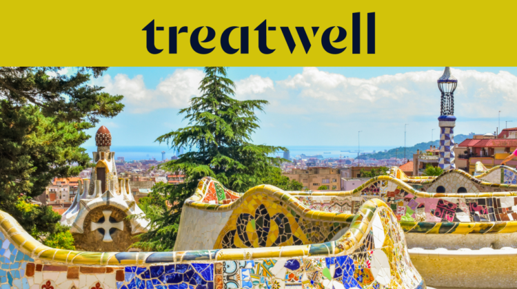 A scenic view of Barcelona from Park Güell, featuring Antoni Gaudís iconic colourful mosaic benches and fairytale-style spires in the foreground, with the city and sea beyond. A large yellow banner at the top displays the "treatwell" logo.
