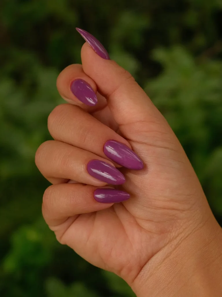 Close-up of a woman's hand with purple almond-shaped acrylic nails