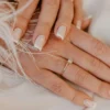 Classic white French tip manicure on natural square-shaped nails resting on white fabric