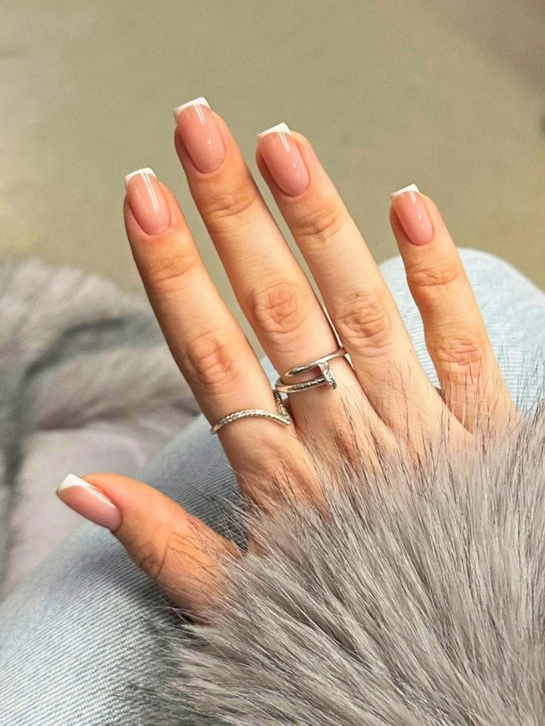 A woman’s hand showing a French tips manicure with micro lines on square nails