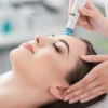 A close-up of a woman relaxing during a HydraFacial treatment with eyes closed in a calm salon setting