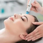 A close-up of a woman relaxing during a HydraFacial treatment with eyes closed in a calm salon setting