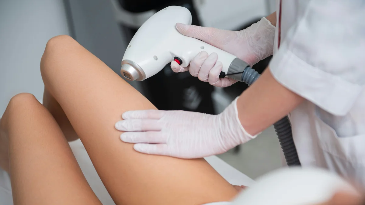 Close-up of a therapist treating a client’s lower leg in a laser hair removal appointment