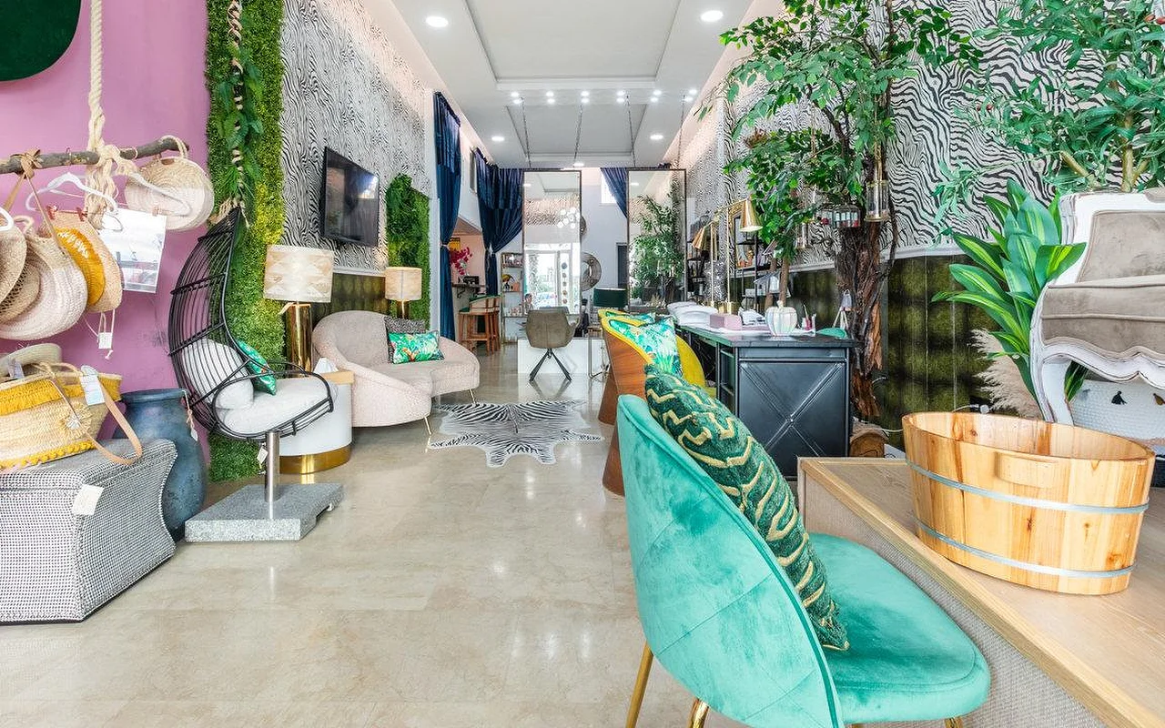 The interior of Brazilian Beauty Marbella, a bright salon with zebra-print walls, a green living-plant wall, teal velvet chairs and a wooden pedicure basin.