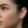 Studio shot of a woman with a curated ear stack showing multiple lobe piercings and a helix hoop