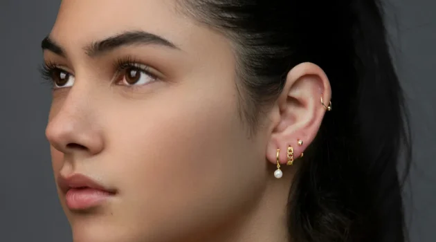 Studio shot of a woman with a curated ear stack showing multiple lobe piercings and a helix hoop