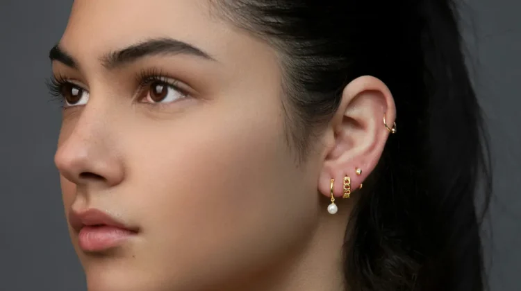 Studio shot of a woman with a curated ear stack showing multiple lobe piercings and a helix hoop