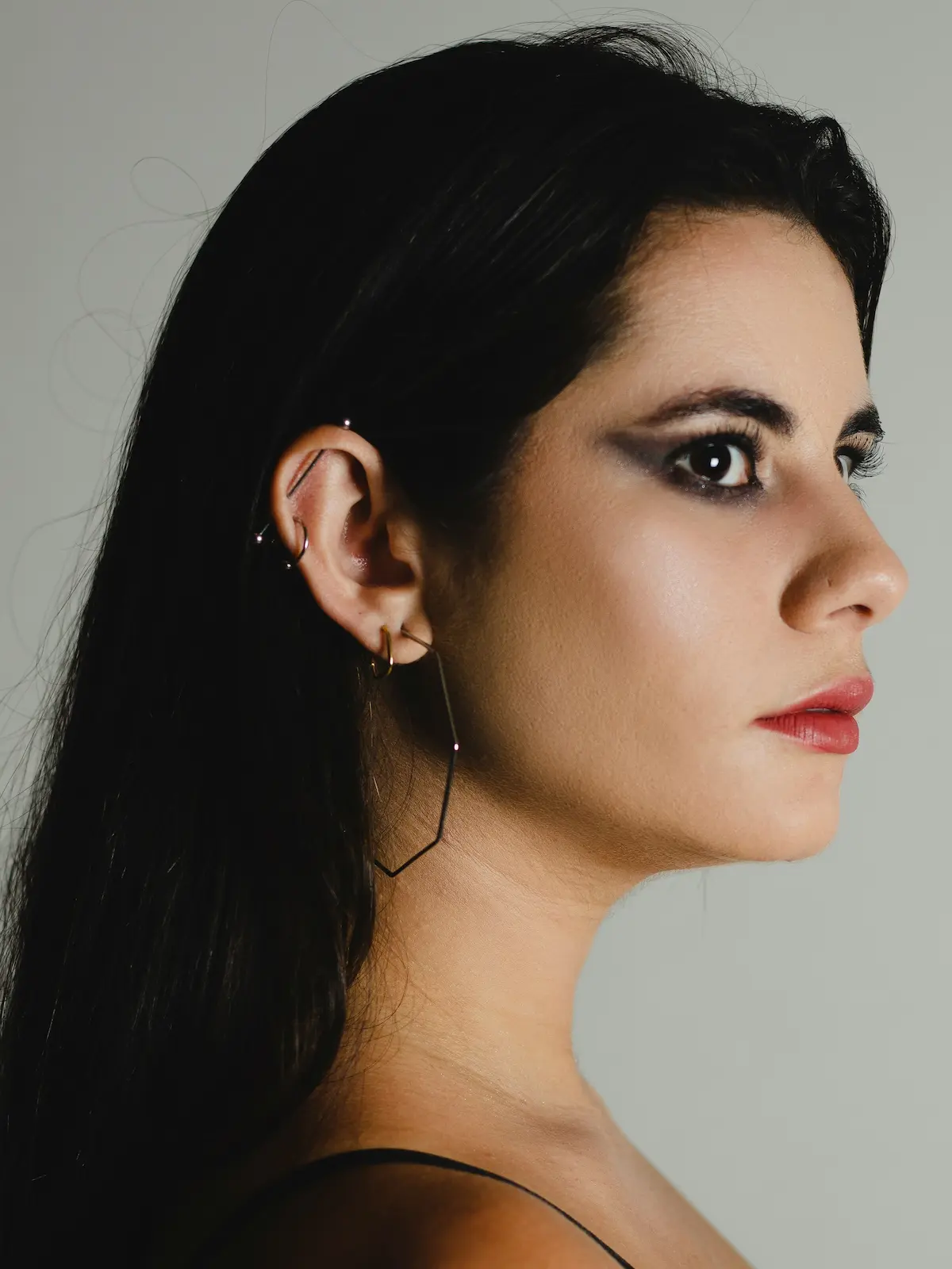 Studio shot of a woman with an industrial barbell, lobe and helix piercings