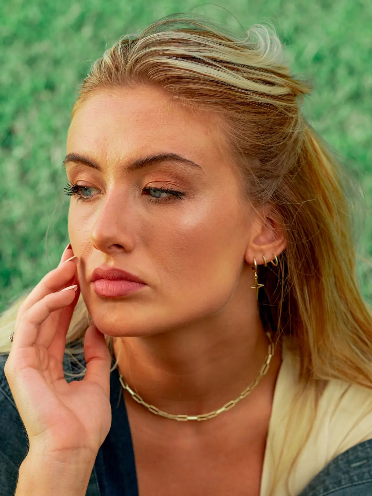 Woman sitting outside on grass with three mini hoop earrings in her lobe