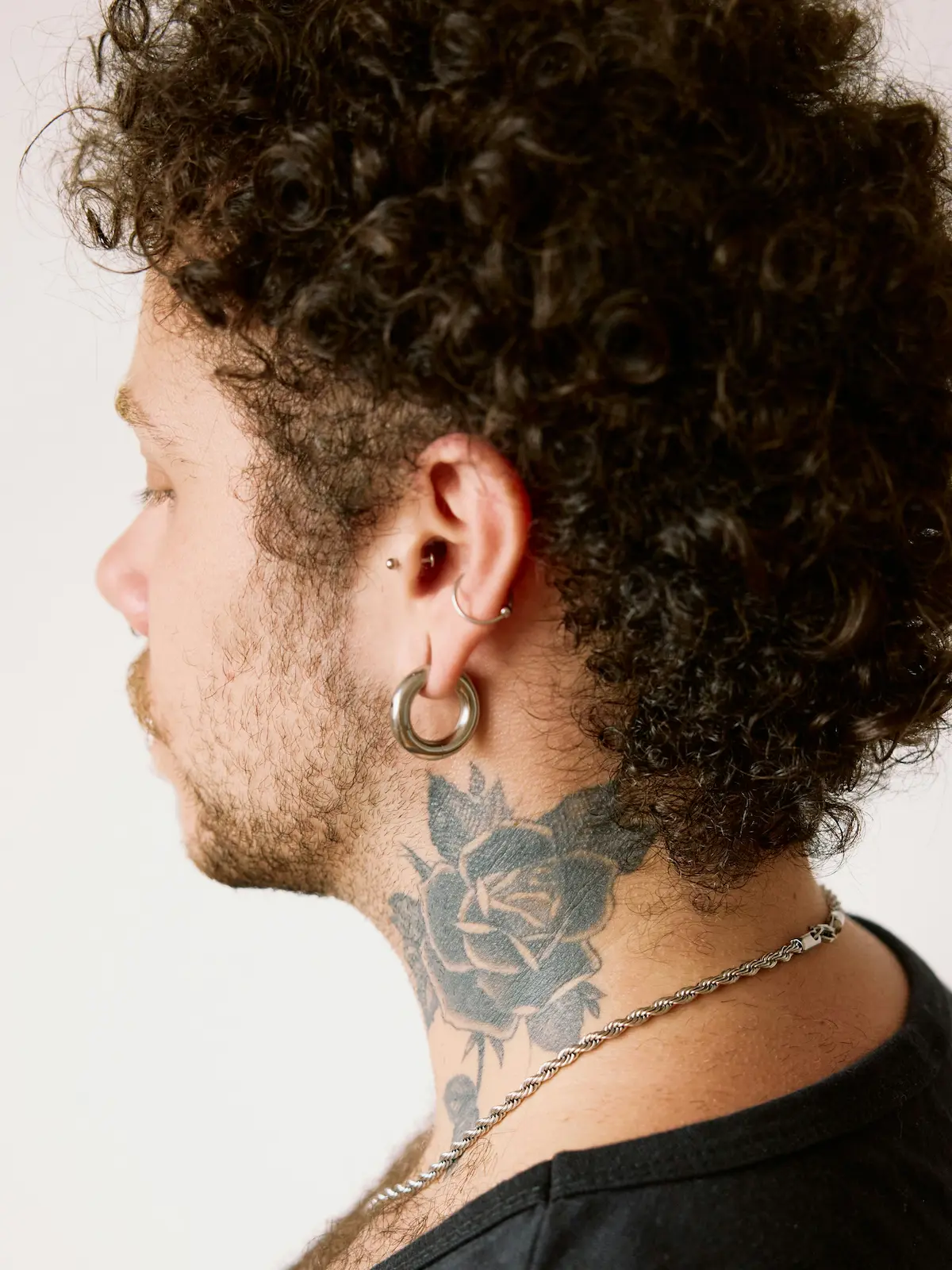 Behind shot of a man with lobe, helix and tragus piercings