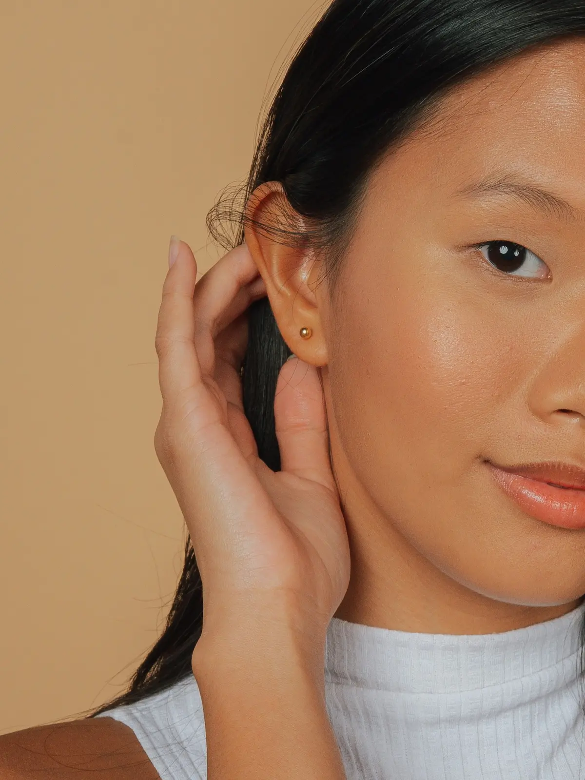 Studio shot of young woman with a single gold stud lobe piercing