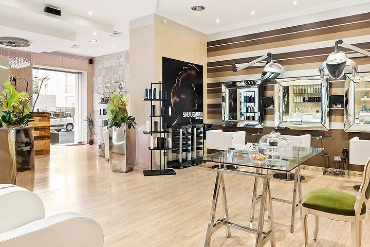 Elegant styling stations at Hair Queen salon in Cagliari with cream and brown striped walls and tall silver planters.