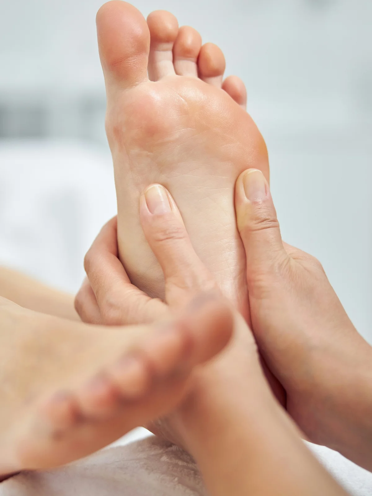Close-up of a technician massaging a client’s foot during a dry pedicure