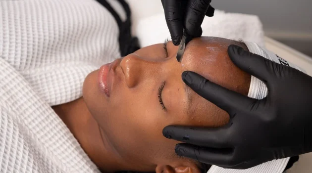 Close-up of an aesthetician performing dermaplaning on a client in salon