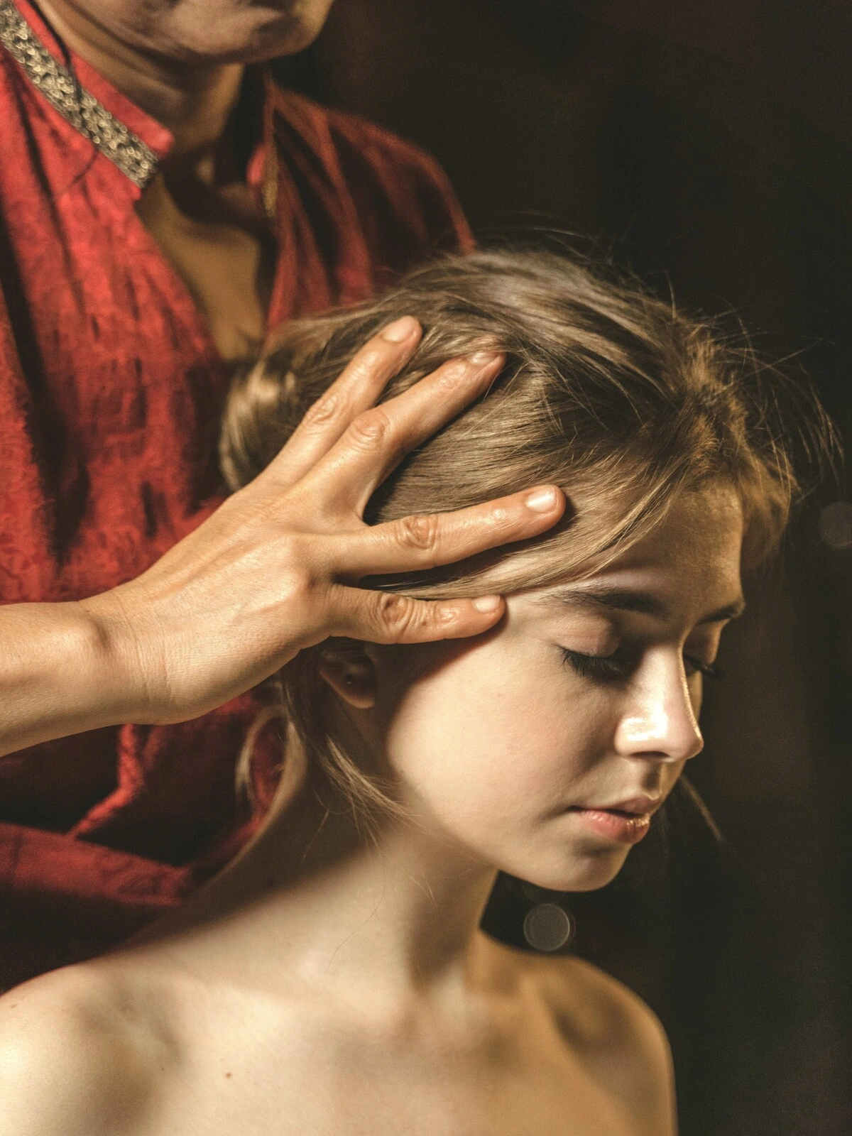 Close-up of a woman with her eyes closed as a therapist massages her scalp during an Indian head massage