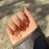 Lava nail art with amber and red swirls on a sheer base