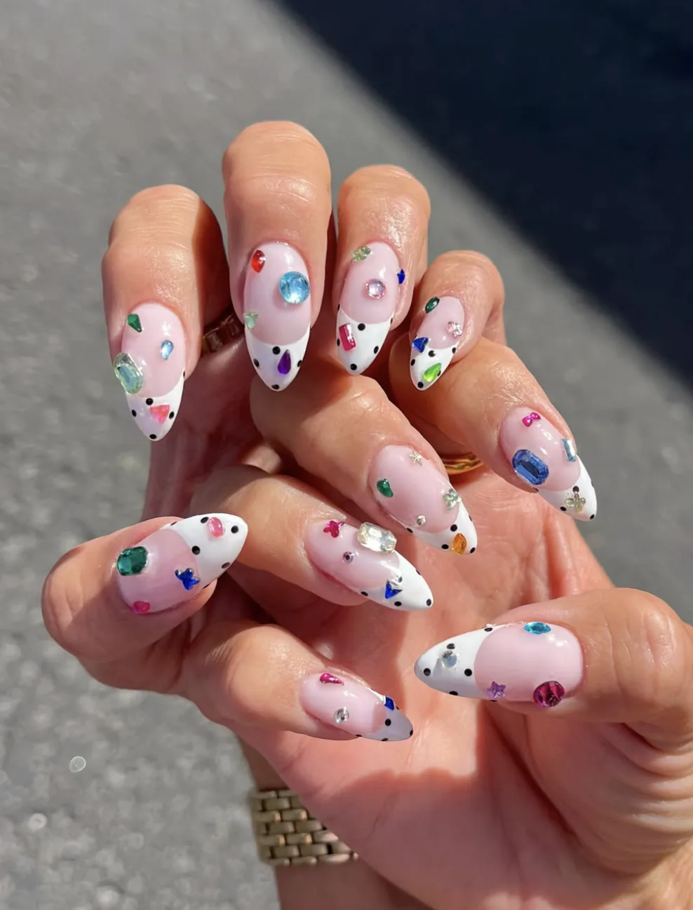 Bedazzled almond nails with colourful rhinestones and polka-dot white tips