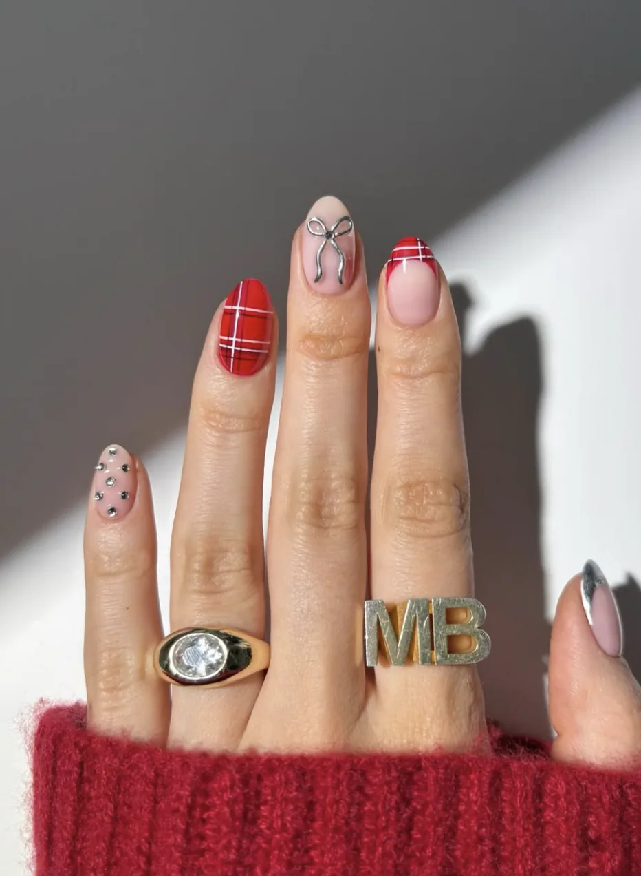 Red tartan nail art paired with a bow design and rhinestone accents